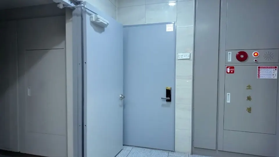 Apartment hallway with a gray door and a fire extinguisher cabinet