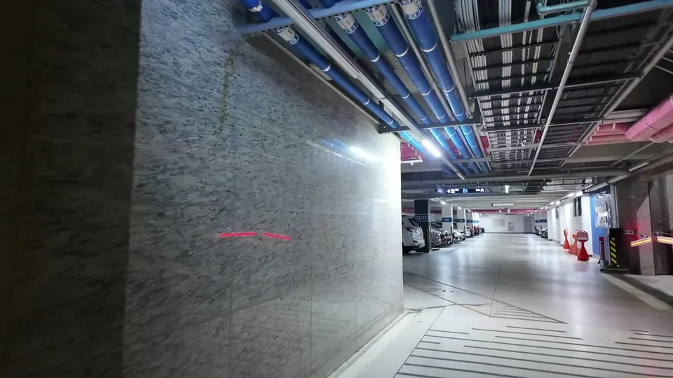 Underground parking garage with blue and pink ceiling pipes and a B1 sign