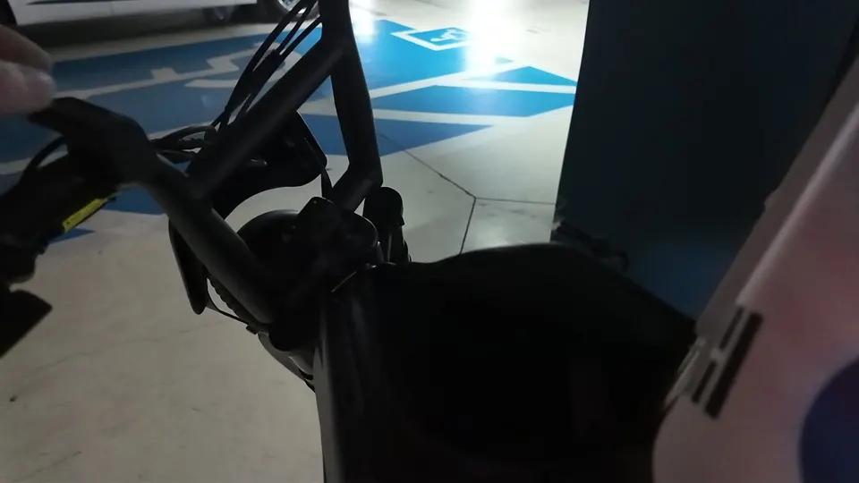 Close view of the kick scooter handlebar and stem with a small Korean flag sticker, blue bay paint on the floor