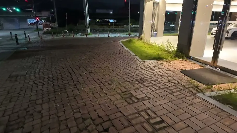 Brick pavement at night in front of a glass showroom