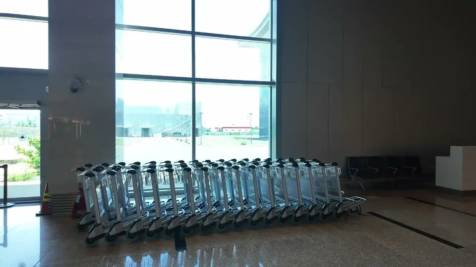 A long row of shiny luggage trolleys lined up in the bright empty arrivals hall at Cam Ranh International Airport