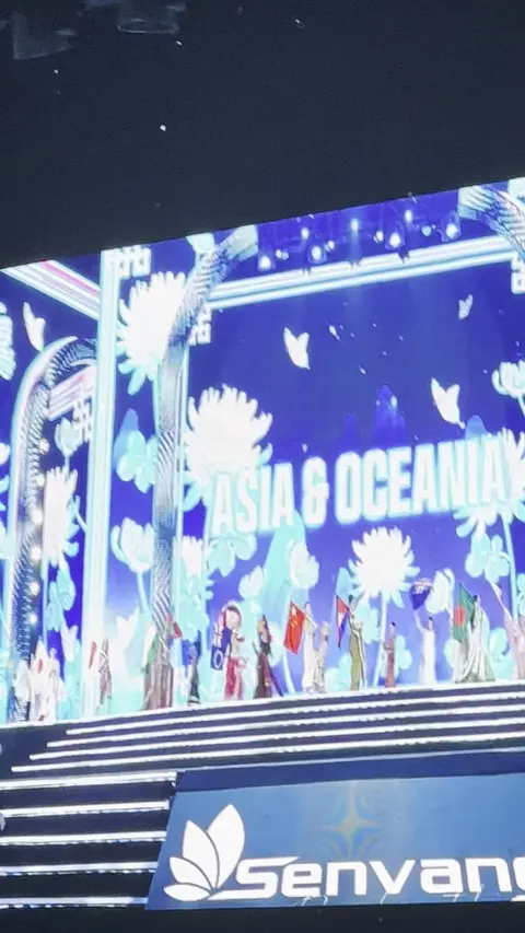 Big screen reading Asia and Oceania above contestants crossing the stage with their national flags