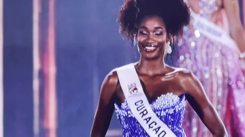 A contestant in a silver gown filling the big screen during her introduction