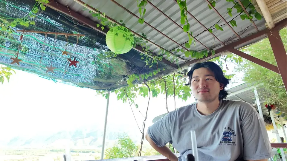 Me sitting under a corrugated roof with a green paper lantern, vines and hanging starfish decorations
