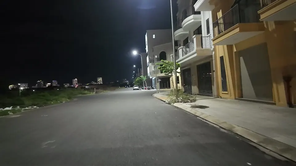 Empty new road at night lined with dark, unoccupied shophouses under street lamps