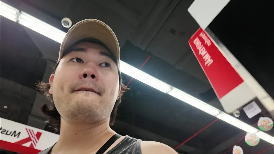 Eddie in a beige cap looking up inside a supermarket with red signs above