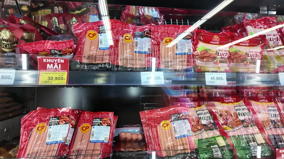 Fridge shelves of packaged frankfurters and sausages with promotion tags