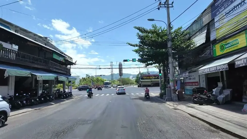 Leaving the Nha Trang city center intersection under a green light, shop houses on both sides