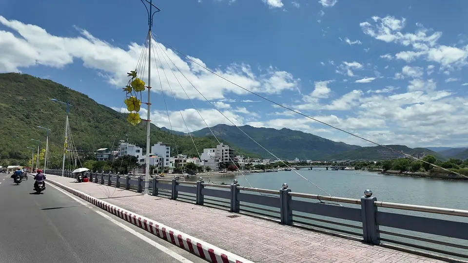 Scooter view crossing a bridge over a river near Nha Trang, hills and town behind