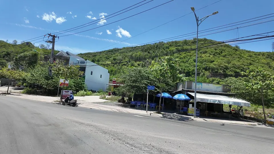 Roadside stalls with blue umbrellas beside a wide road on the edge of town
