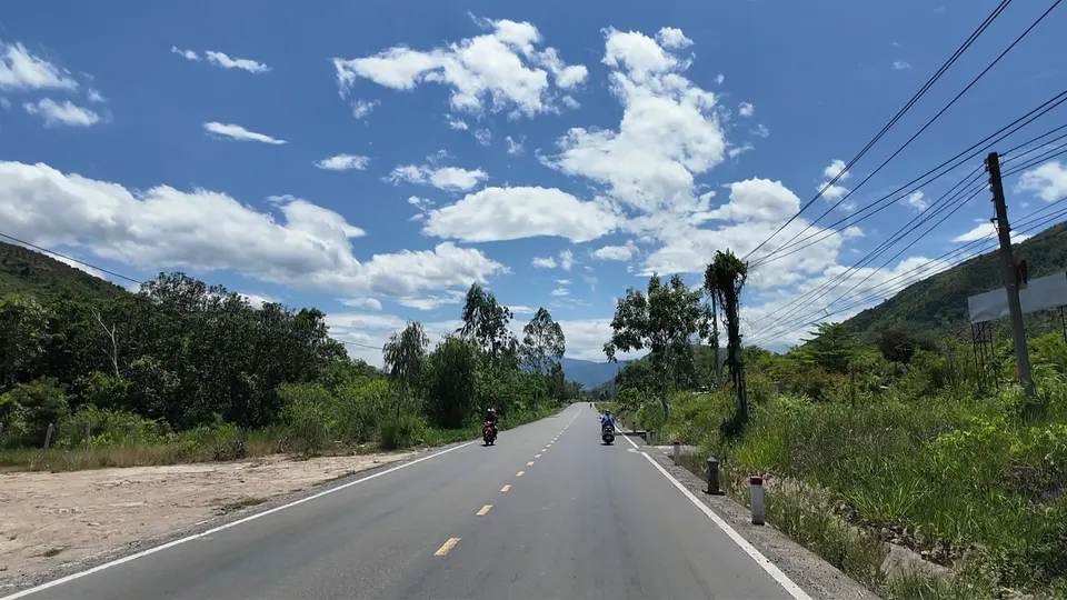 Empty two lane road with a yellow centre line under a sky full of clouds