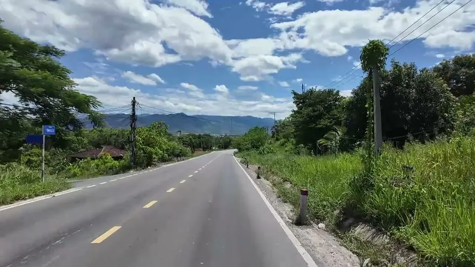 Empty road curving toward a wall of mountains under big clouds