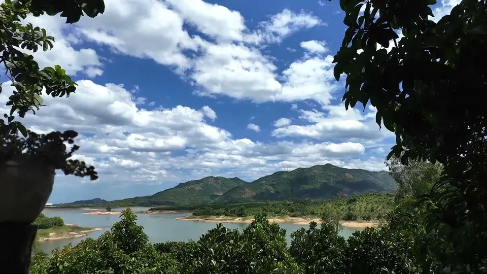 Lake framed by trees, with green water, sandbars, and mountains ringing the far shore